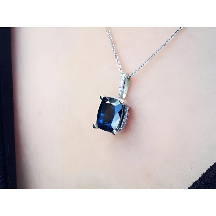 4.11 ct deep blue cushion cut sapphire pendant in 14K white gold, worn on a neck.