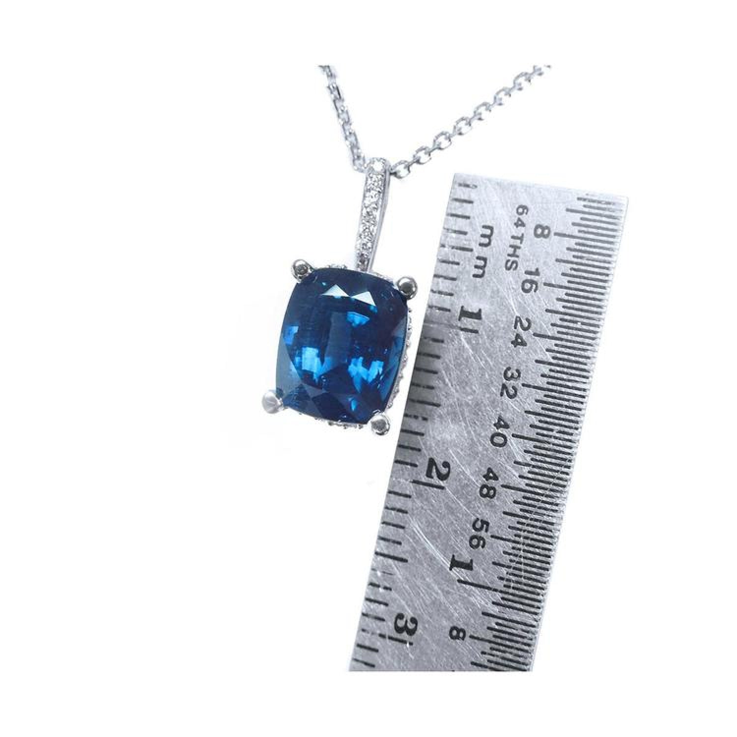 4.11 ct cushion cut deep blue sapphire pendant in 14K white gold with a ruler for scale.