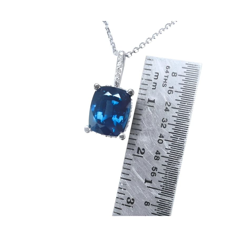 4.11 ct cushion cut deep blue sapphire pendant in 14K white gold with a ruler for scale.