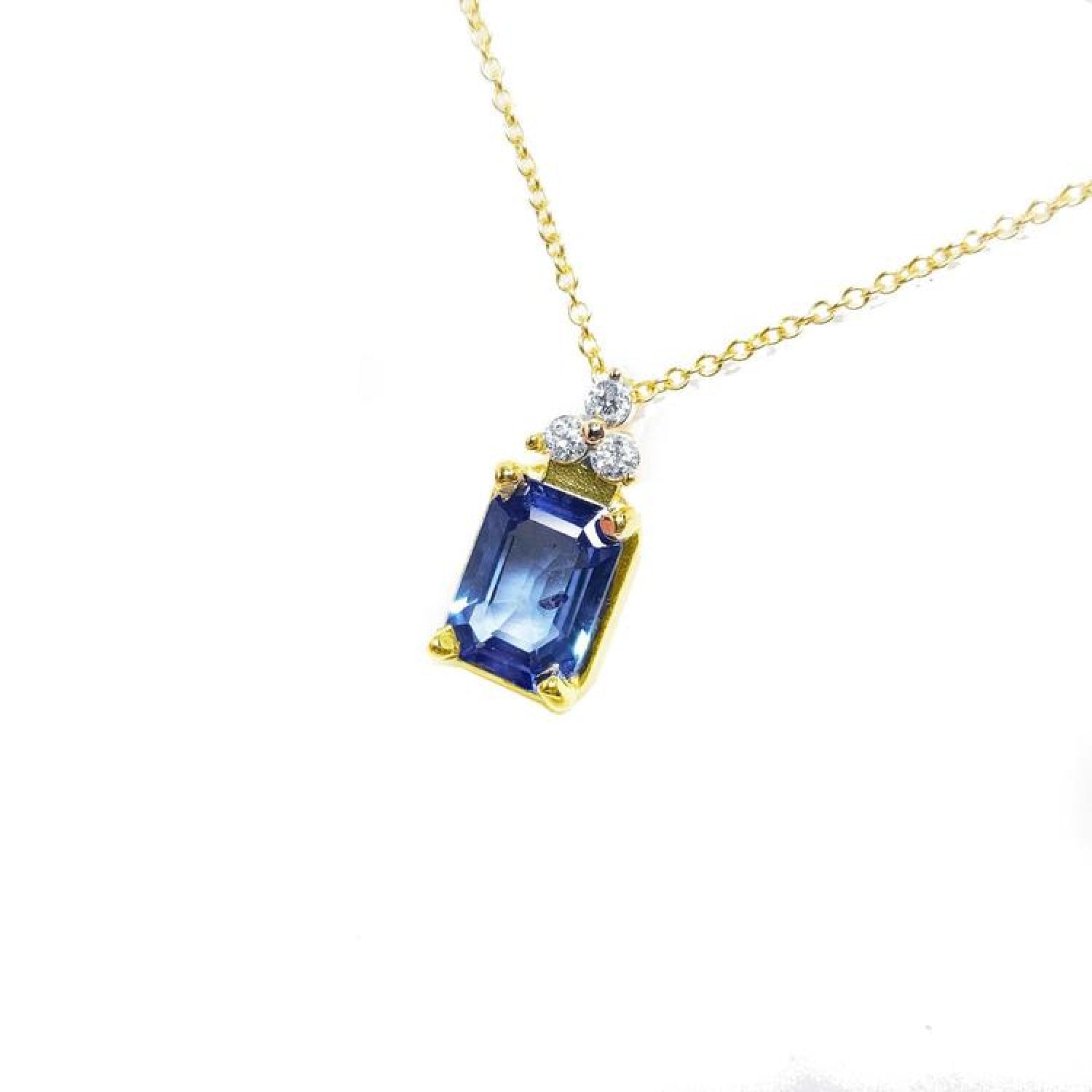 14k gold necklace with an emerald-cut blue sapphire pendant and three diamond accents.