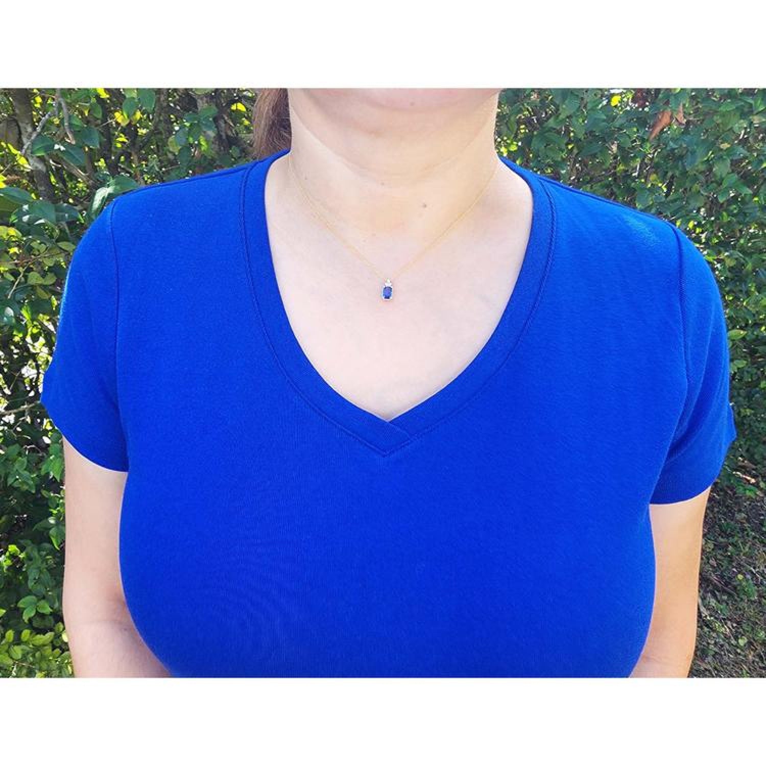 Woman wearing a 14k gold necklace with an emerald-cut blue sapphire pendant and diamond accents.