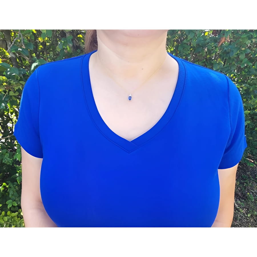 Woman wearing a 14k gold necklace with an emerald-cut blue sapphire pendant and diamond accents.