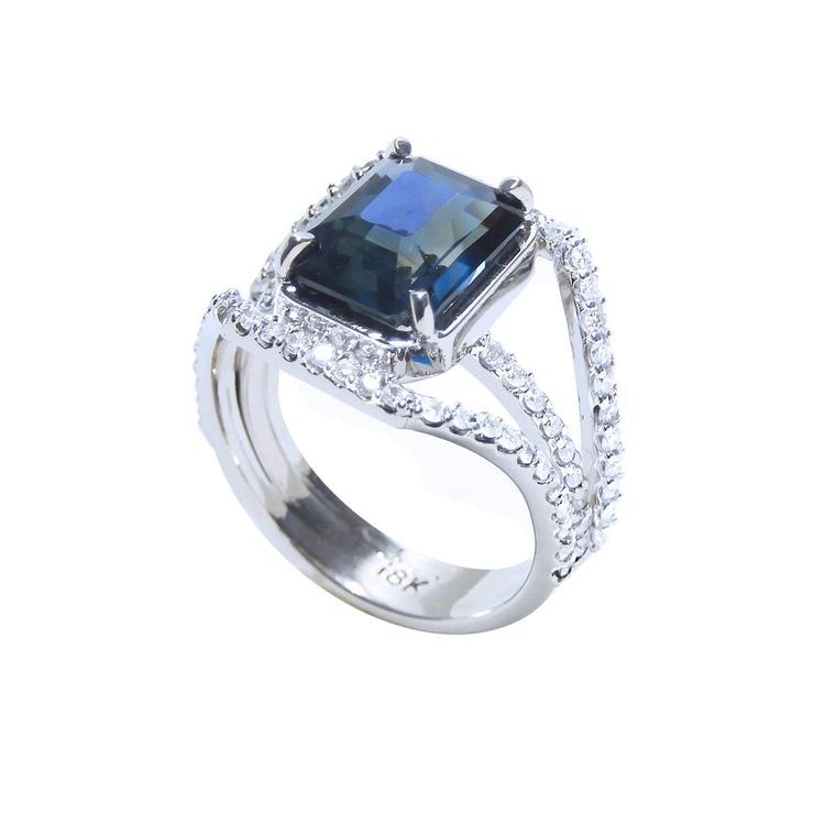 Emerald cut 4.51 ct. blue sapphire ring in 18K gold with a three-row diamond band.