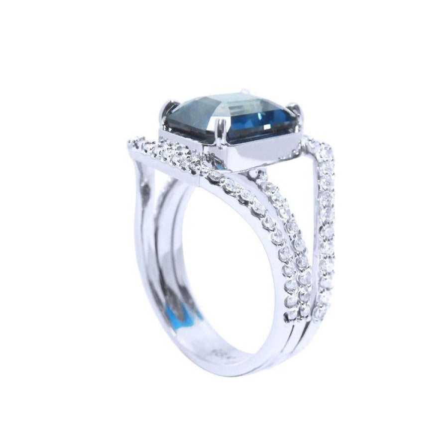 18K white gold ring with a 4.51 ct emerald-cut blue sapphire and a three-row diamond band.