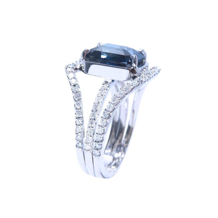 18K white gold ring with a 4.51 ct emerald cut blue sapphire and a three-row diamond band.