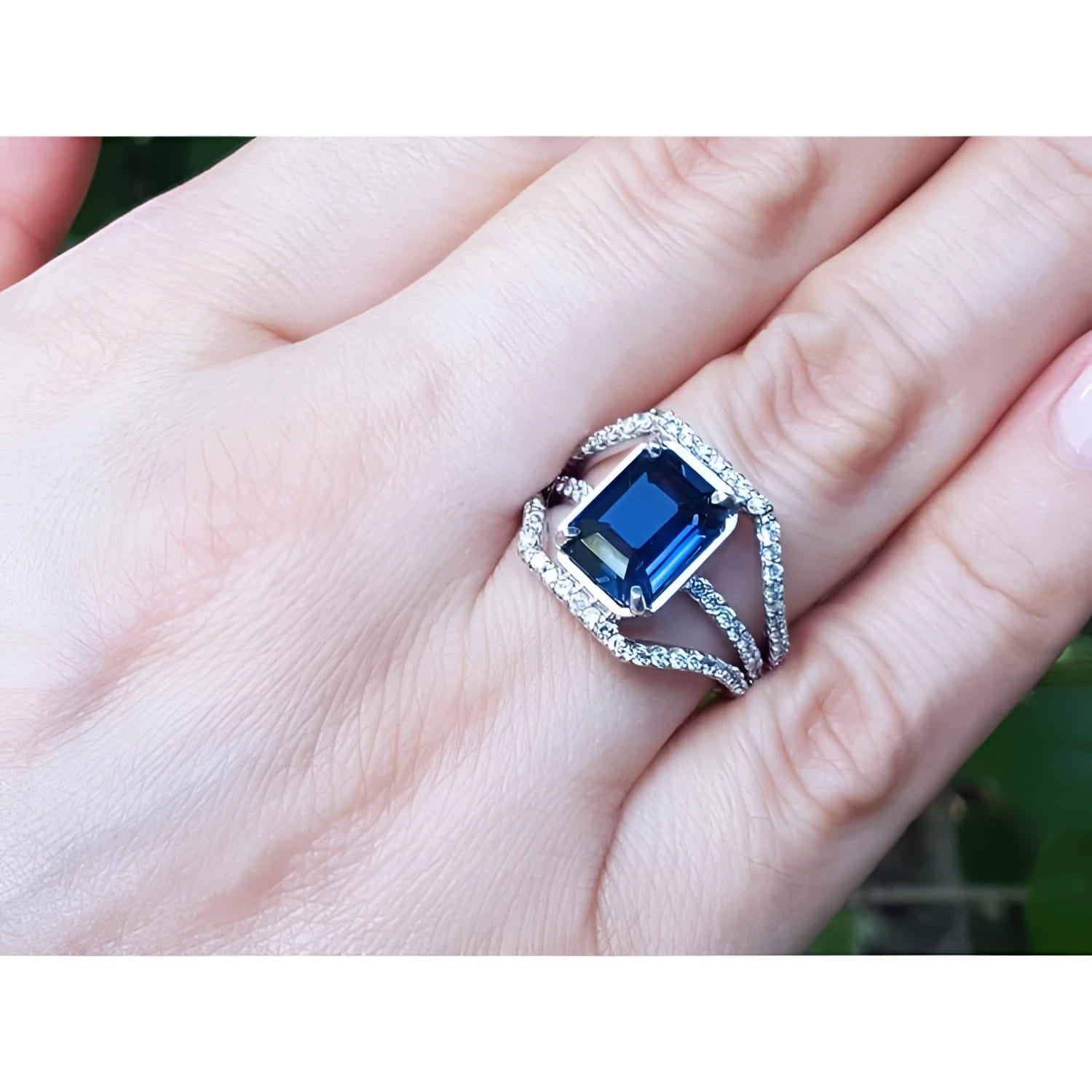 18K gold ring with a 4.51 ct emerald cut blue sapphire and a three-row diamond band.