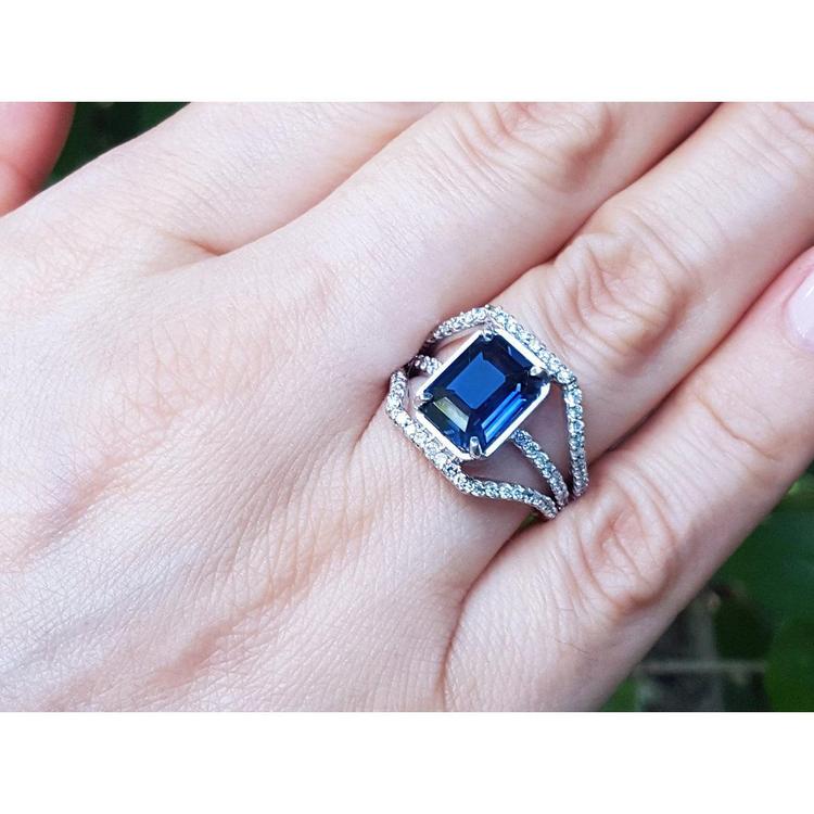 18K gold ring with a 4.51 ct emerald cut blue sapphire and a three-row diamond band.