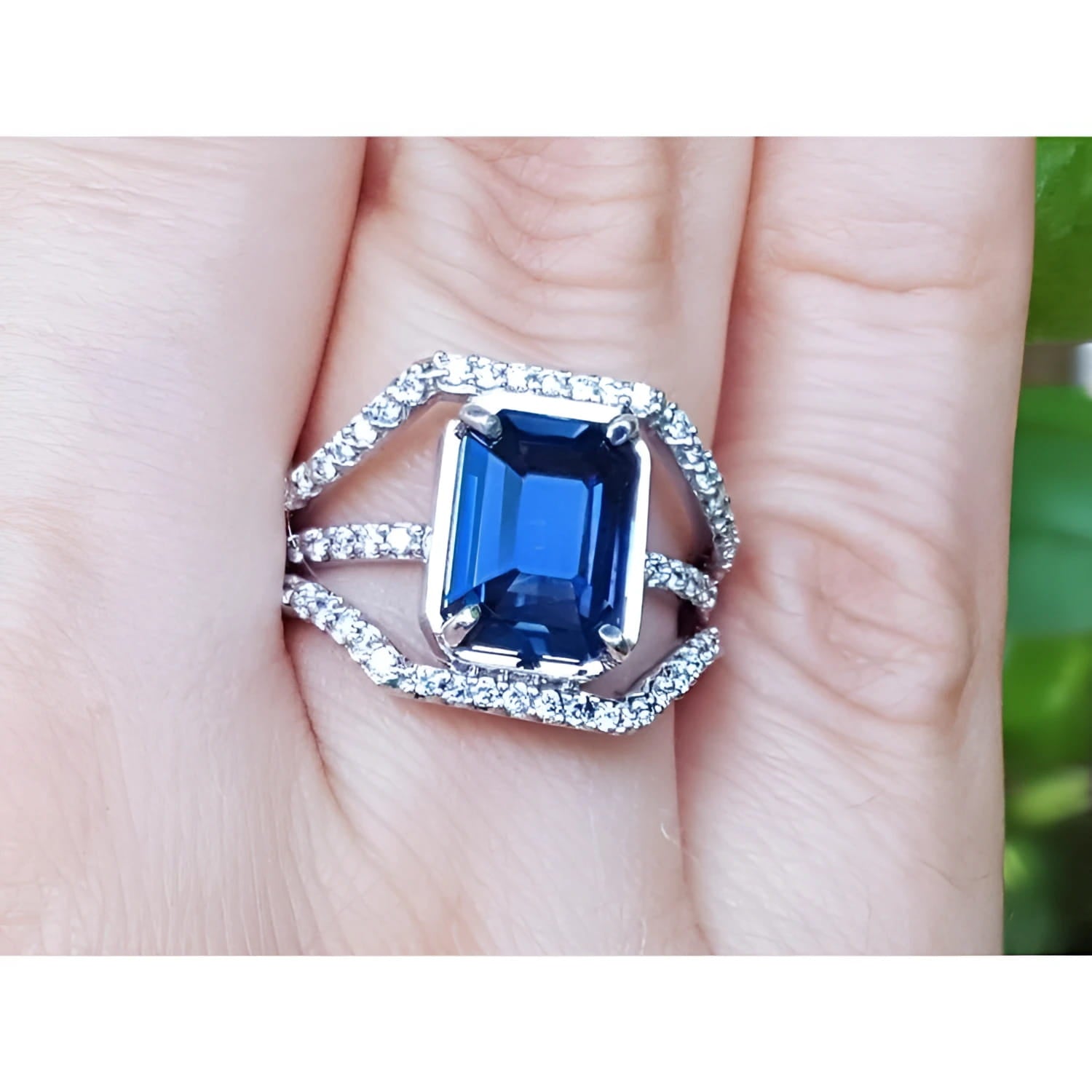 18K gold ring with a 4.51 ct emerald cut blue sapphire and a three-row diamond band.