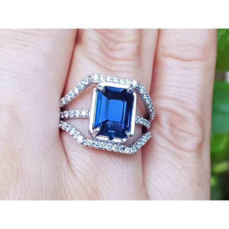 18K gold ring with a 4.51 ct emerald cut blue sapphire and a three-row diamond band.