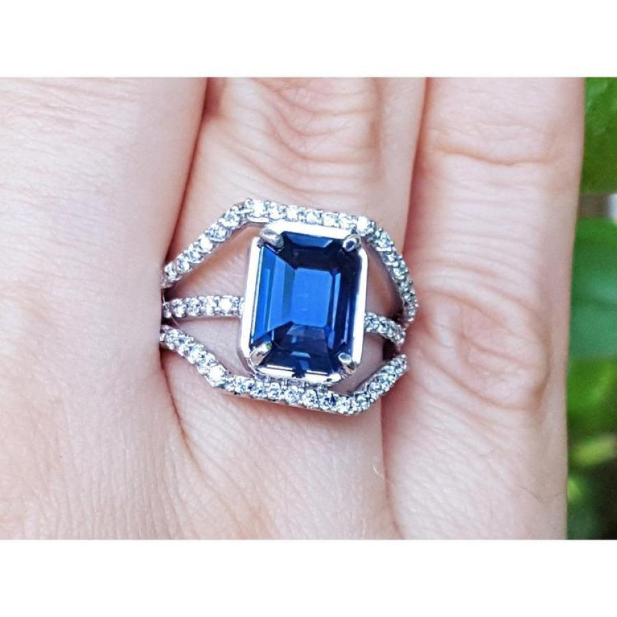18K gold ring with a 4.51 ct emerald cut blue sapphire and a three-row diamond band.