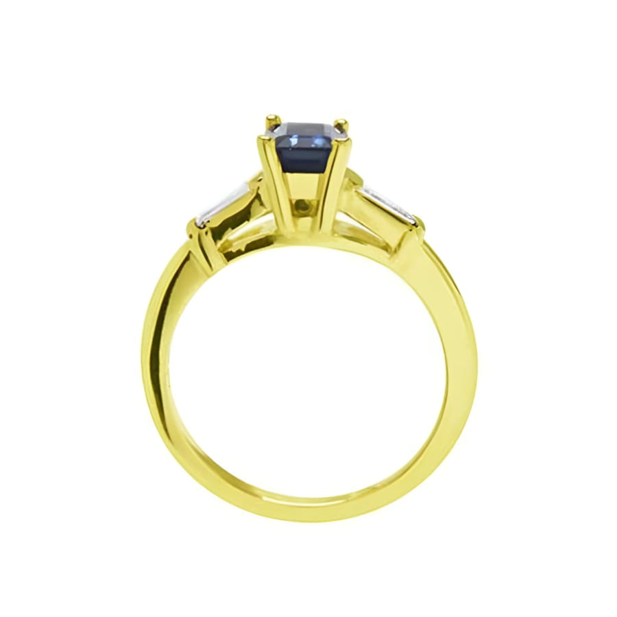 1.13 ct. emerald-cut blue sapphire ring with tapered diamonds in 14K yellow gold.