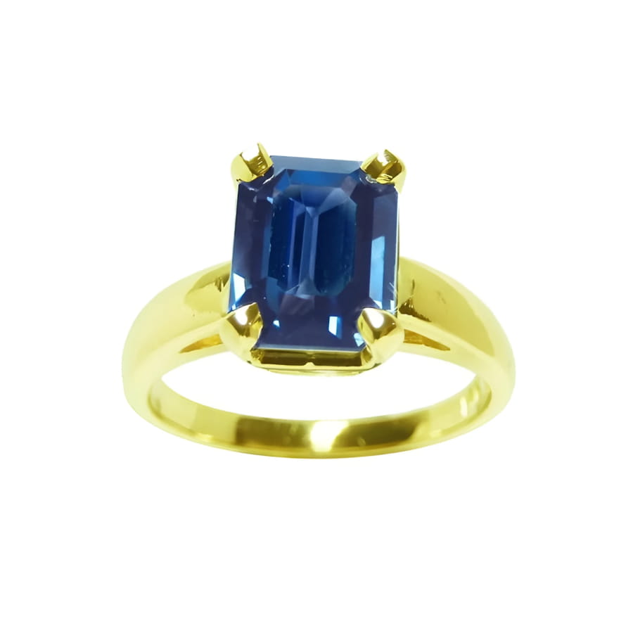 A women’s blue sapphire solitaire ring featuring a deep blue, rectangular emerald-cut sapphire set in 14k yellow gold.