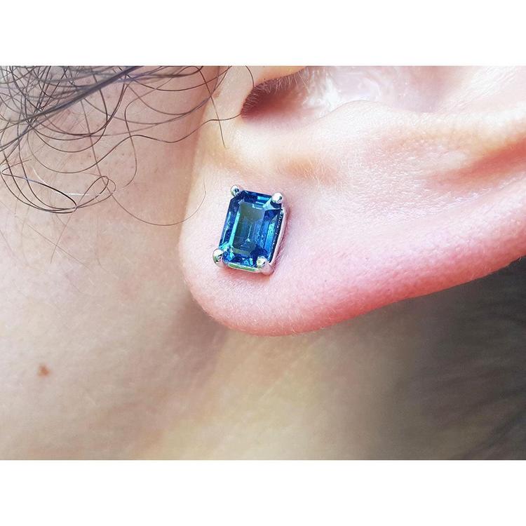 Blue natural sapphire earring on a person's ear