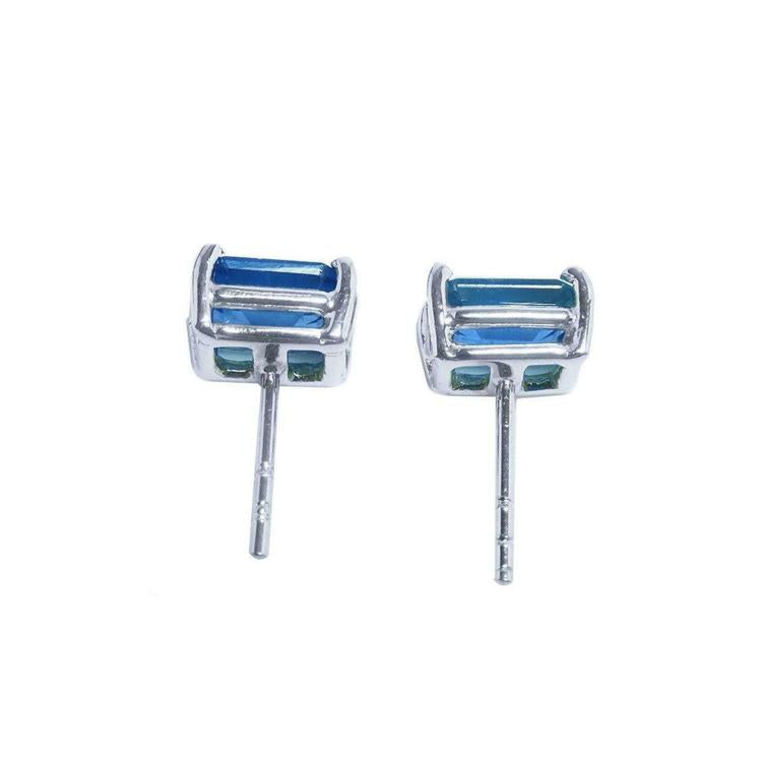Pair of emerald-cut deep blue sapphire stud earrings in 14K white gold, with prong settings and friction backs.