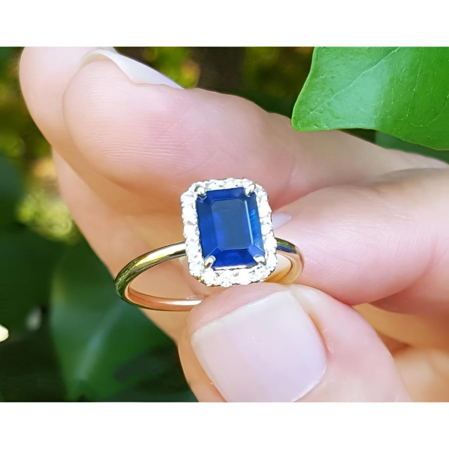 Women's 14k yellow gold ring with emerald-cut blue sapphire and halo diamonds.