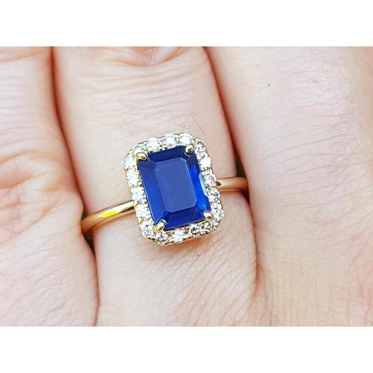 14k yellow gold ring with a natural blue sapphire halo diamond on a finger