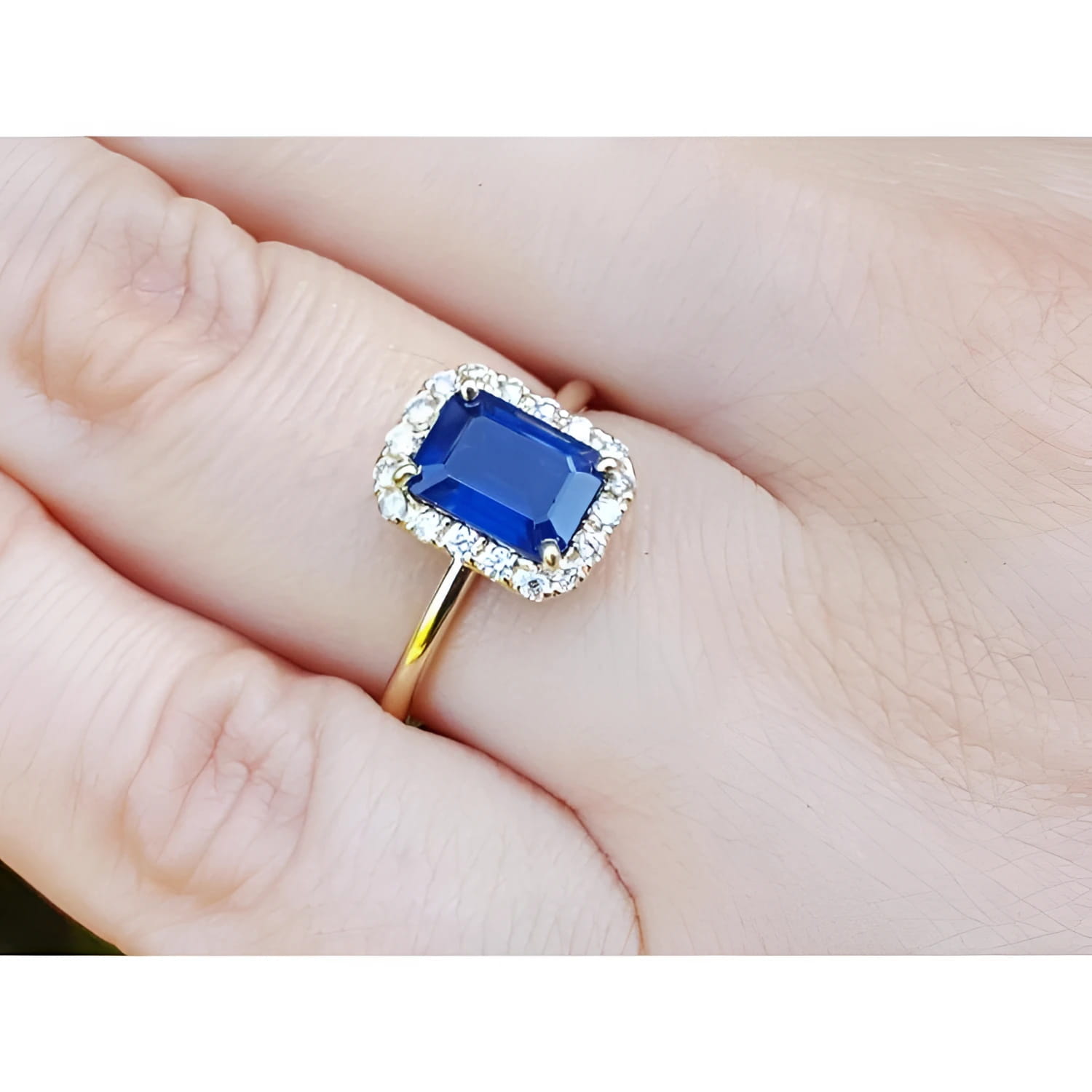 Women's 14k yellow gold ring with emerald-cut blue sapphire and diamond halo.