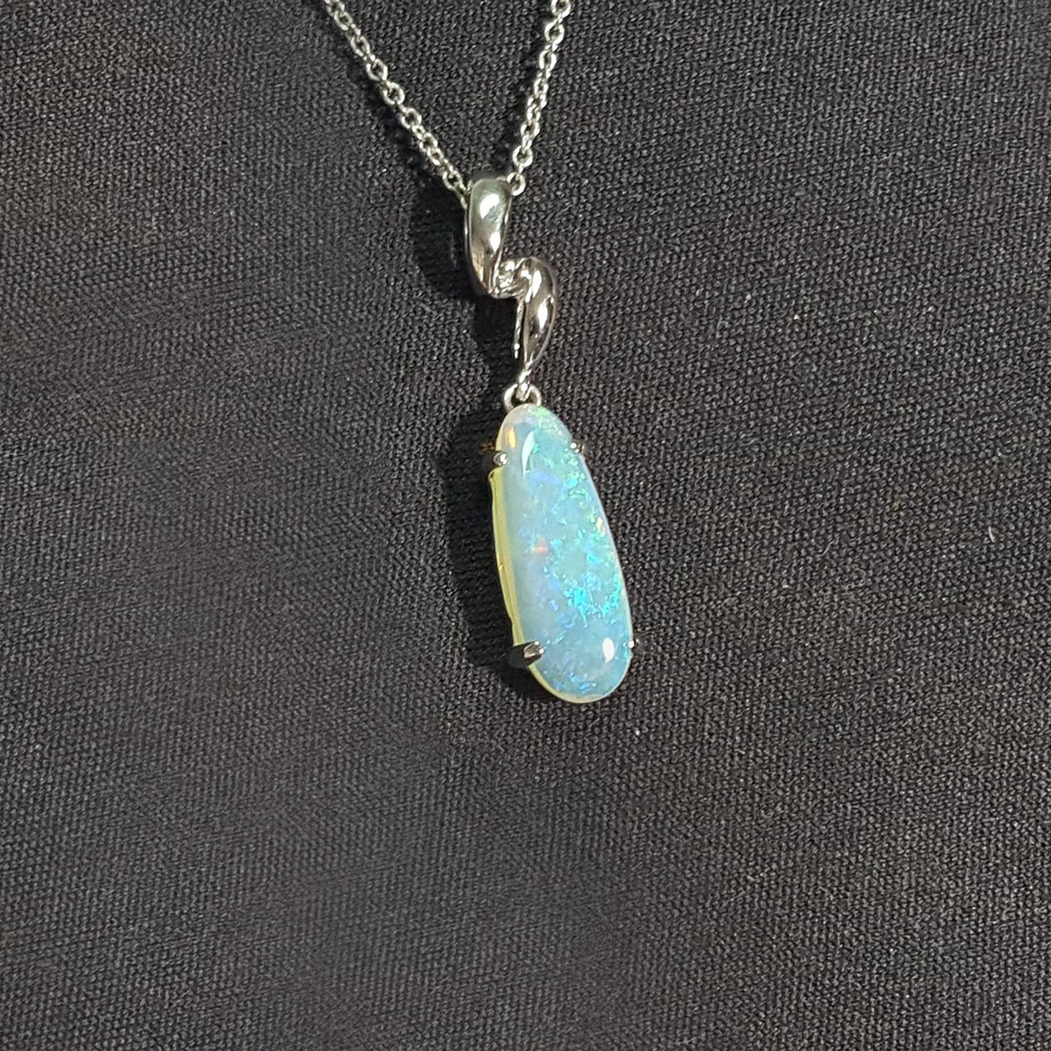 Opal pendant necklace on a dark fabric background