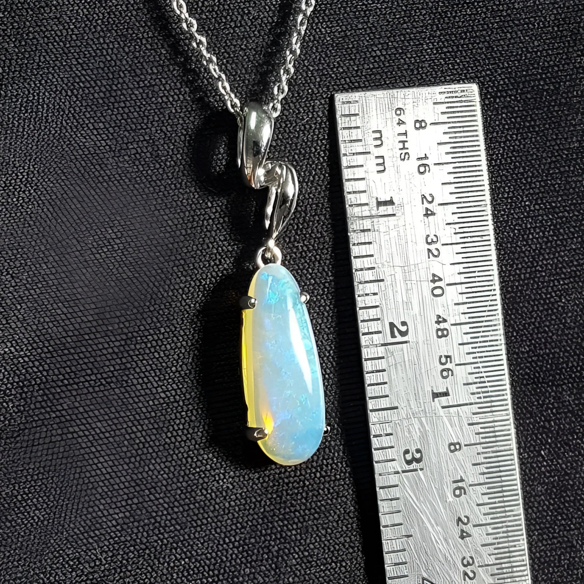 1.56 ct bluish-green opal pendant in 14K white gold, elongated pear shape, next to a ruler.