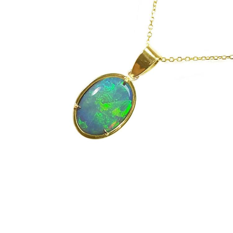 A bluish green opal pendant on a gold chain against a white background