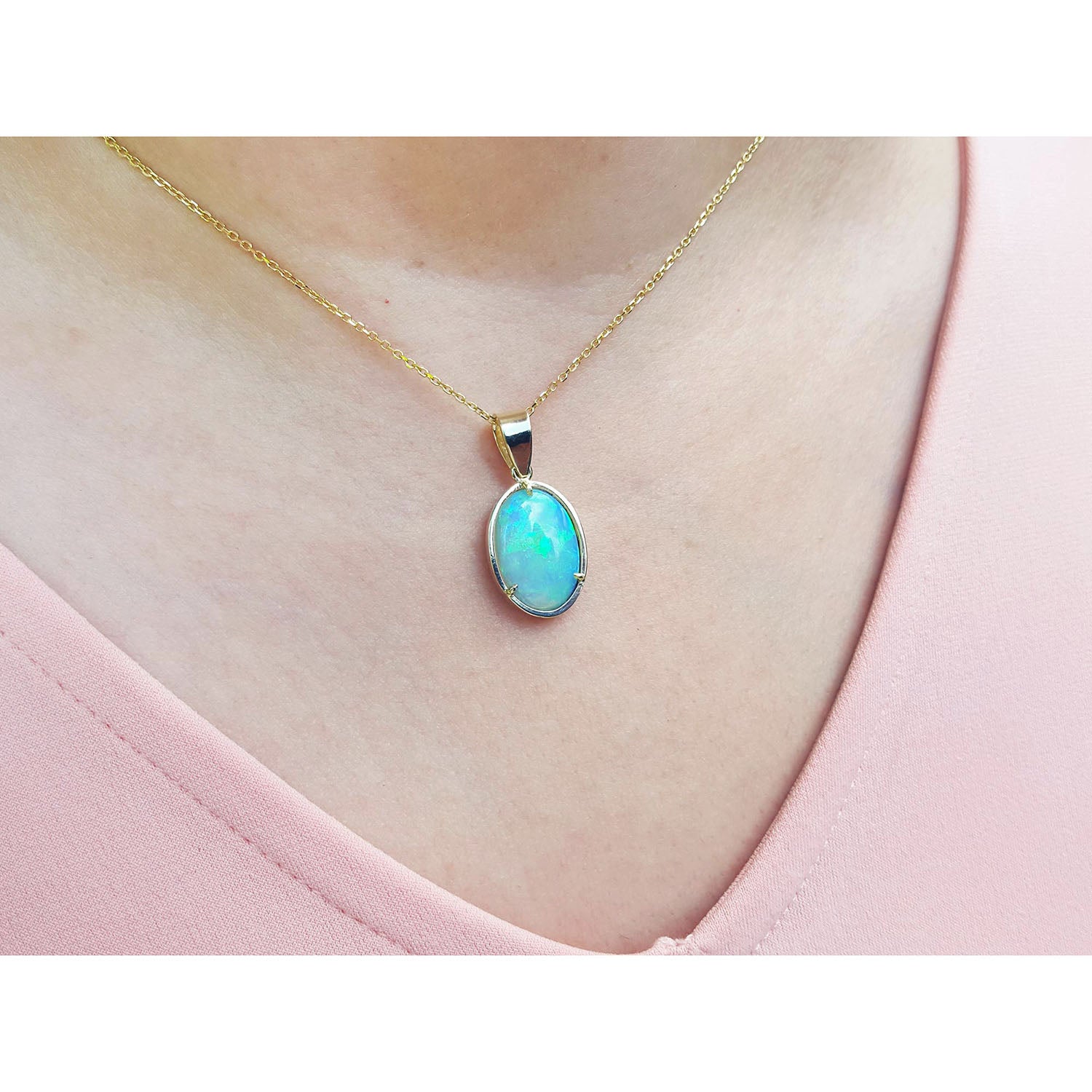 Opal pendant necklace on a person&#39;s neck wearing a pink top.