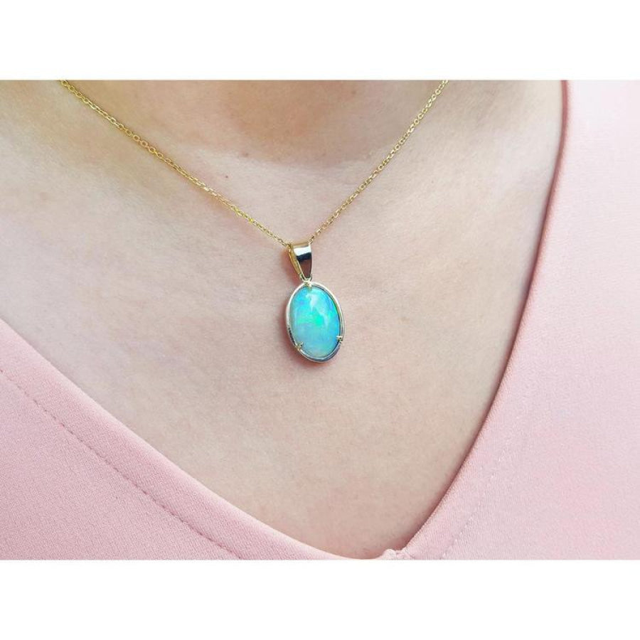 Oval bluish-green Australian opal pendant in 14K yellow gold, worn on a delicate chain.