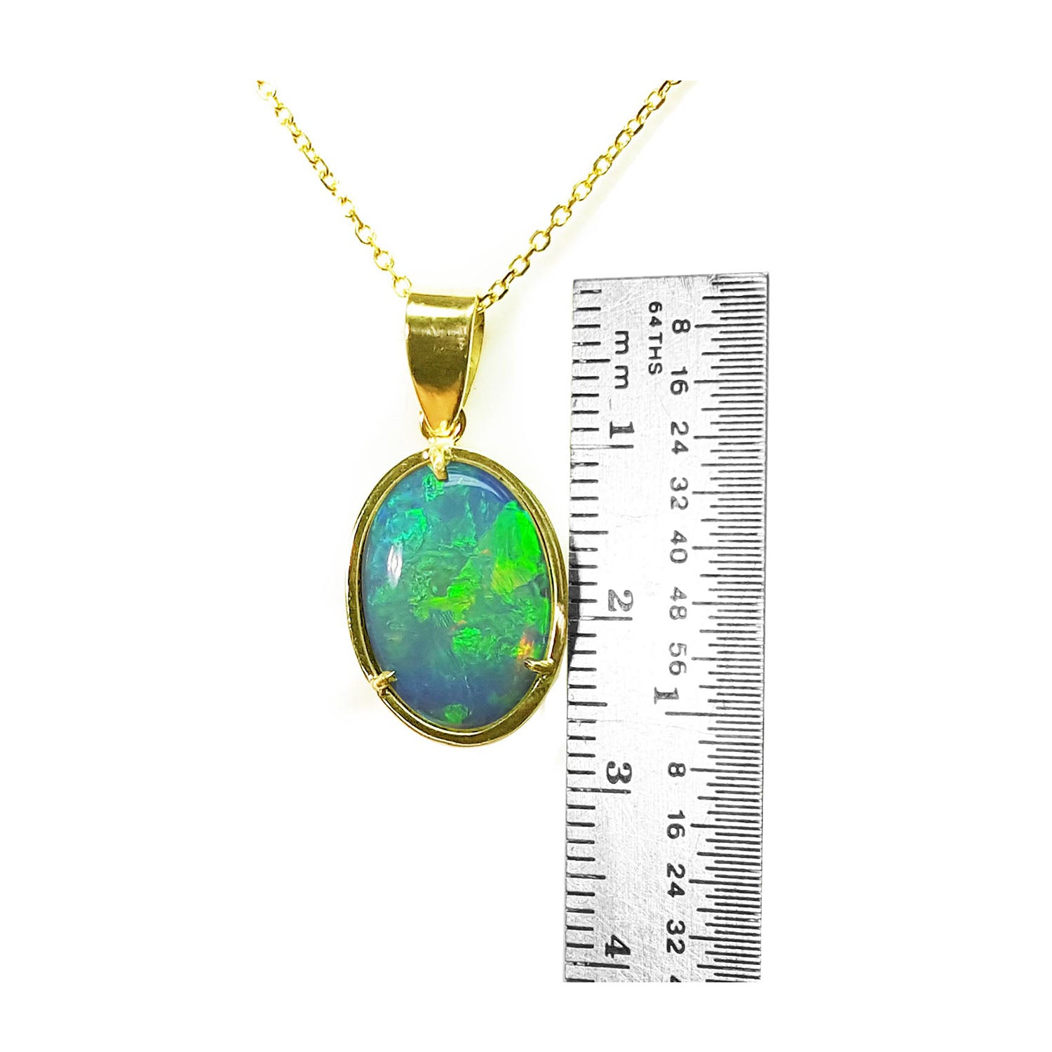 Opal pendant on a gold chain with a ruler for scale on a white background