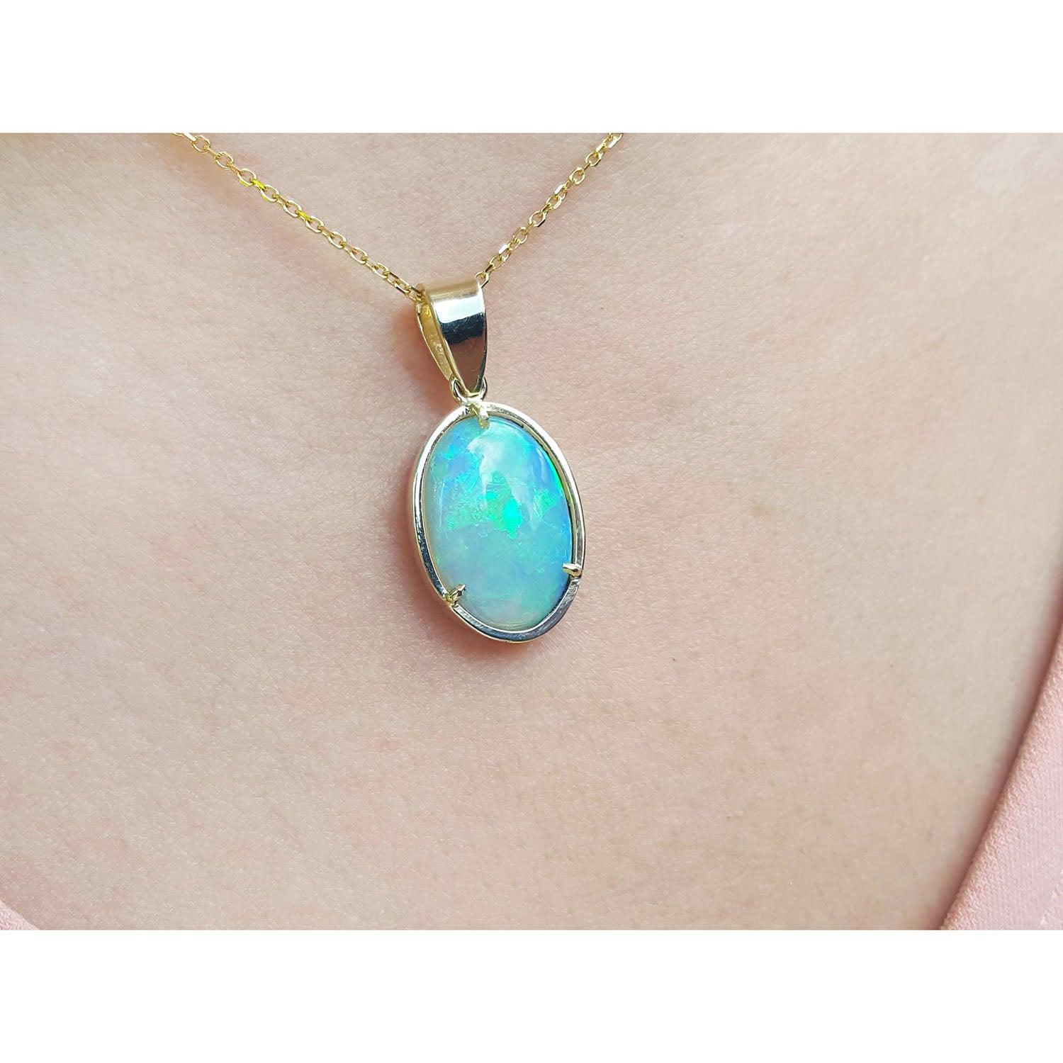 Opal pendant necklace on a gold chain against a skin background.