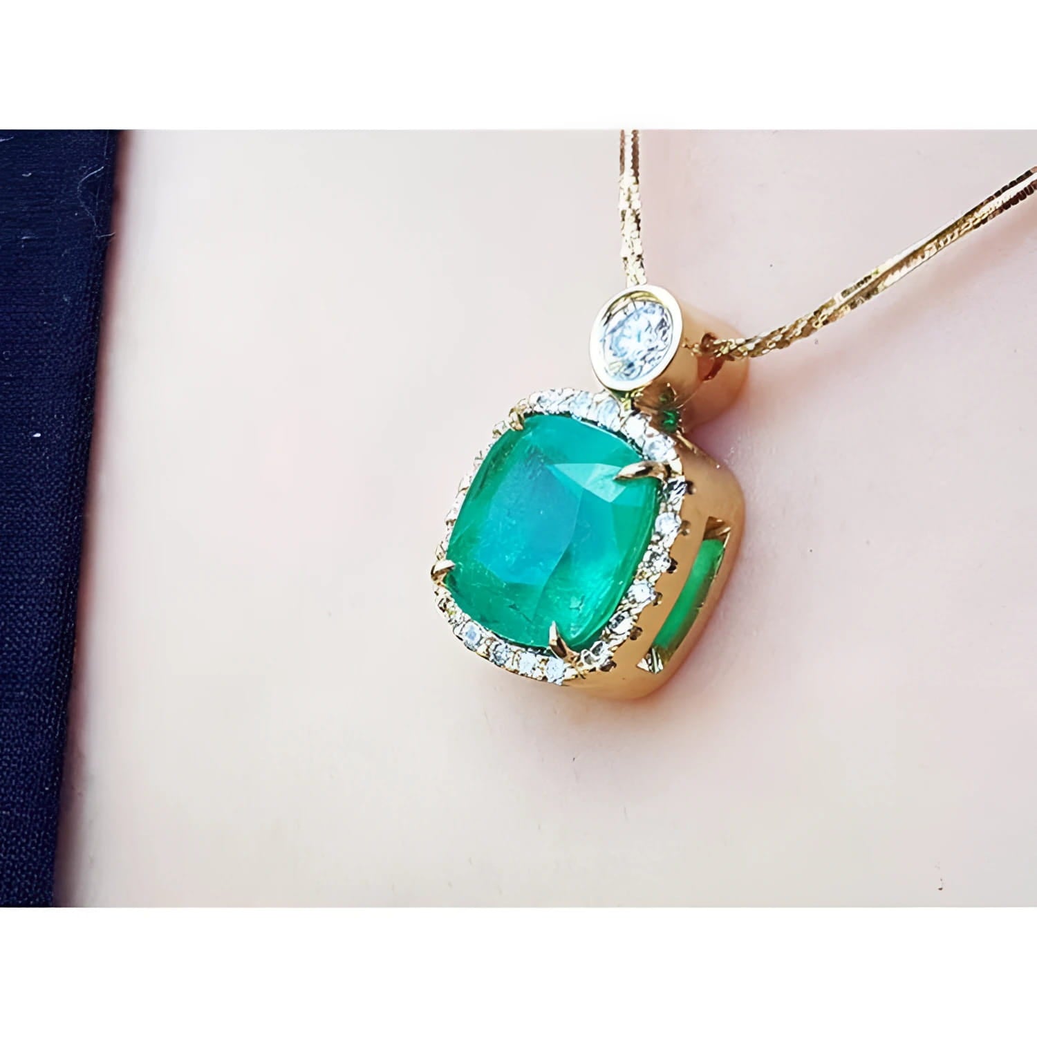 Cushion-cut Colombian emerald necklace with halo diamonds in 18K yellow gold.