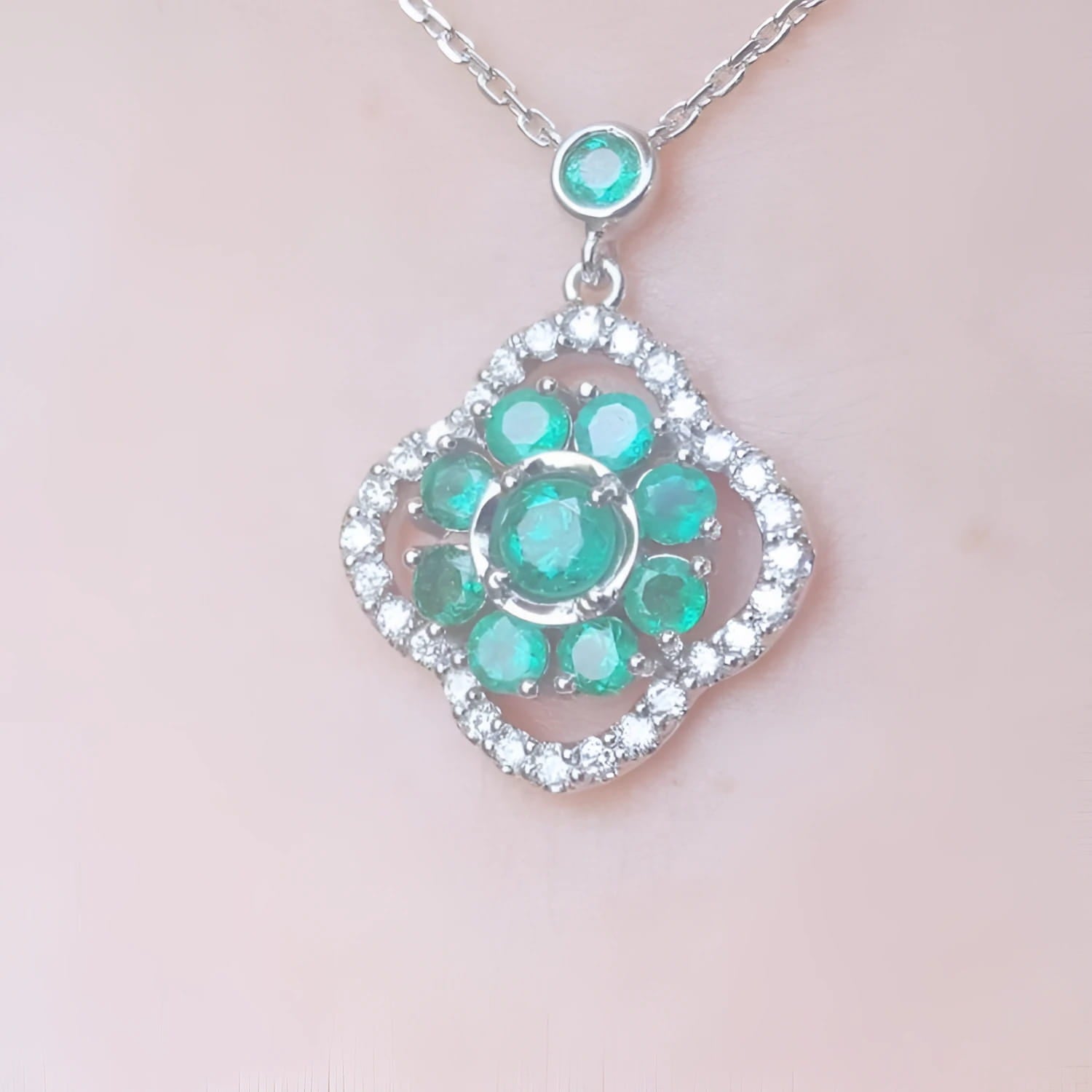 14K white gold cluster necklace with natural Colombian emeralds and diamond 4-leaf clover silhouette.