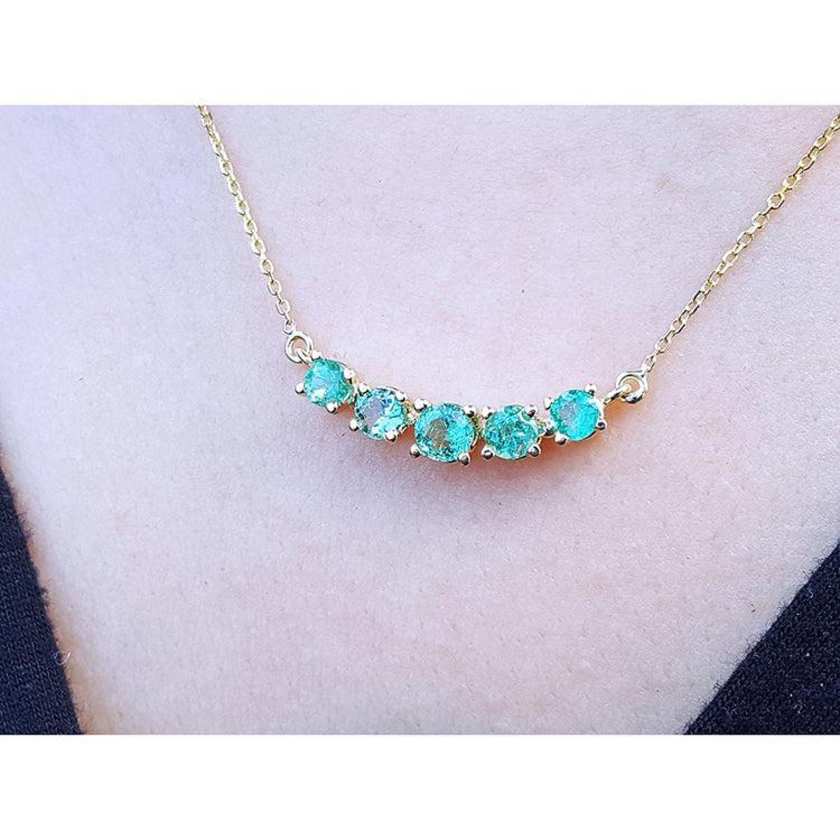 14K gold necklace with five sparkling round-cut green fire emeralds.
