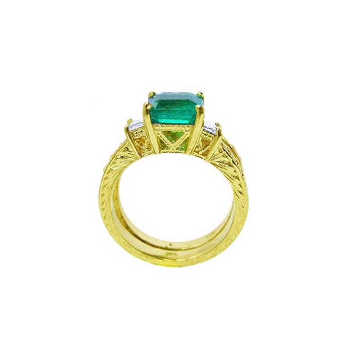 A lateral view of a natural emerald ring bridal style, top setting, gallery and band ring visibles.