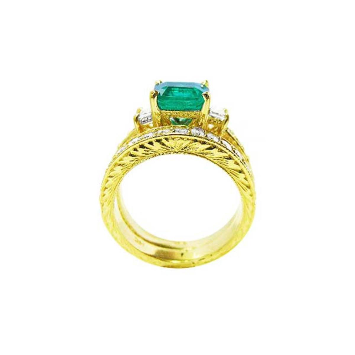 Lateral profile view of a bridal wedding band with diamonds in front of the main emerald ring.