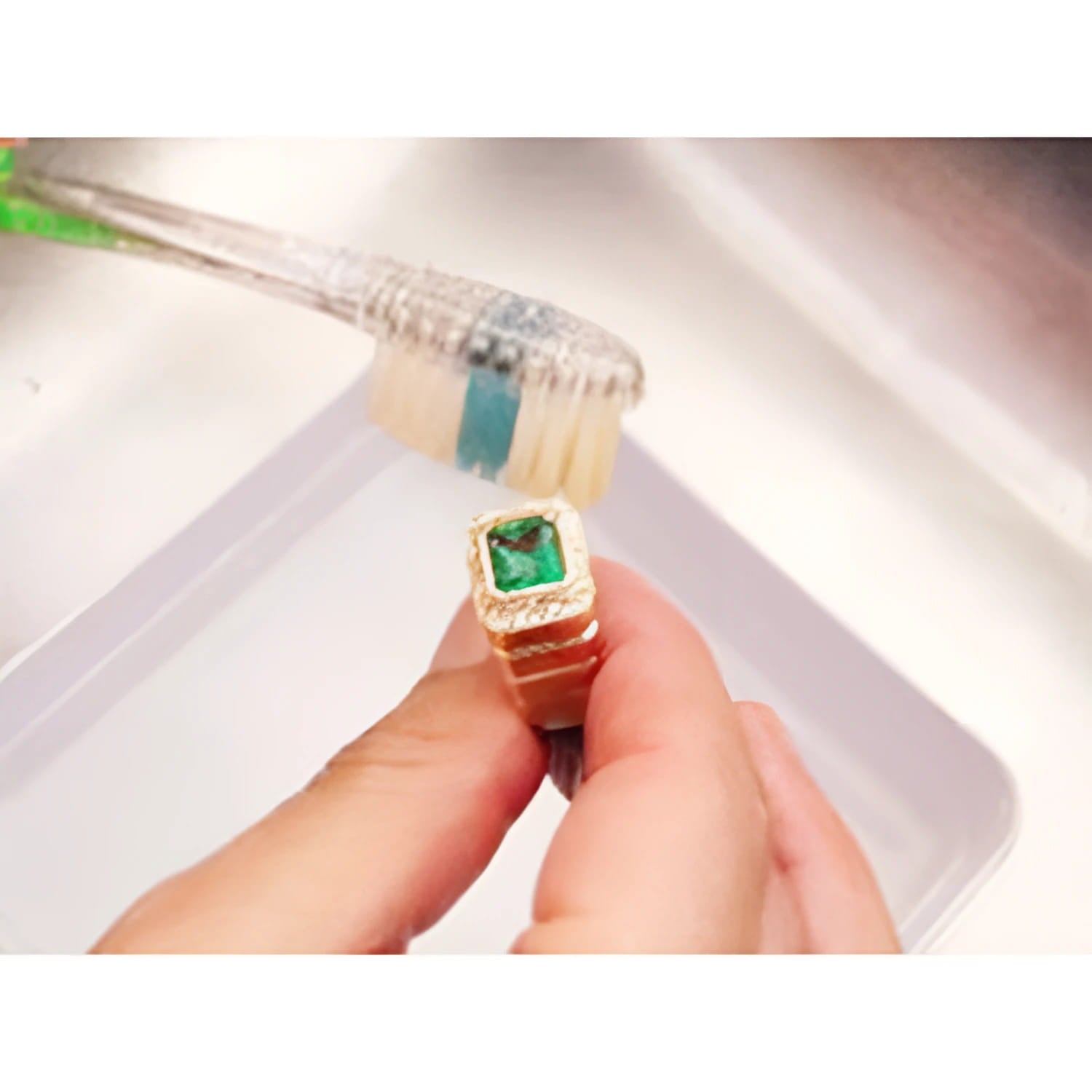 Brushing emerald ring on top side main gemstone and accent diamonds removing dirt