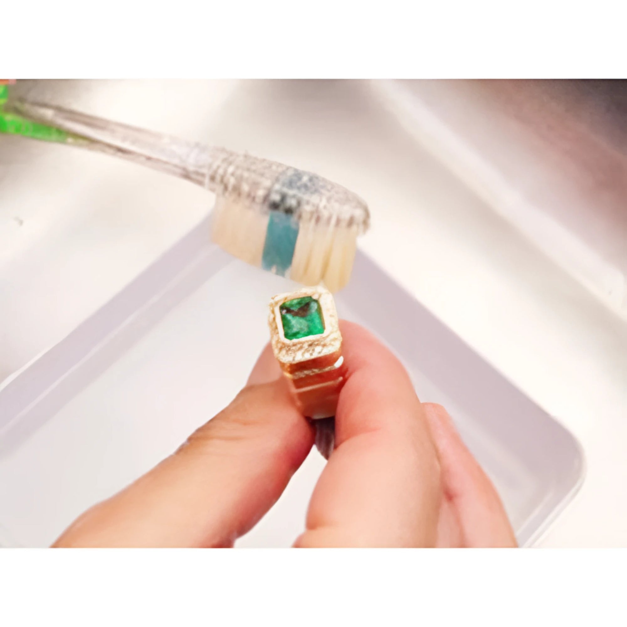Brushing emerald ring on top side main gemstone and accent diamonds removing dirt