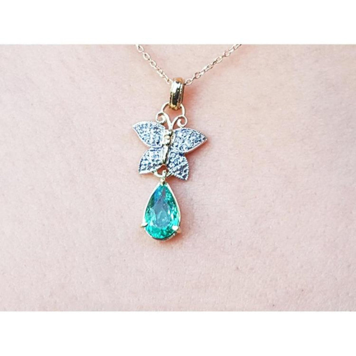 14K gold butterfly pendant with pavé diamonds and a pear-shaped Colombian emerald.