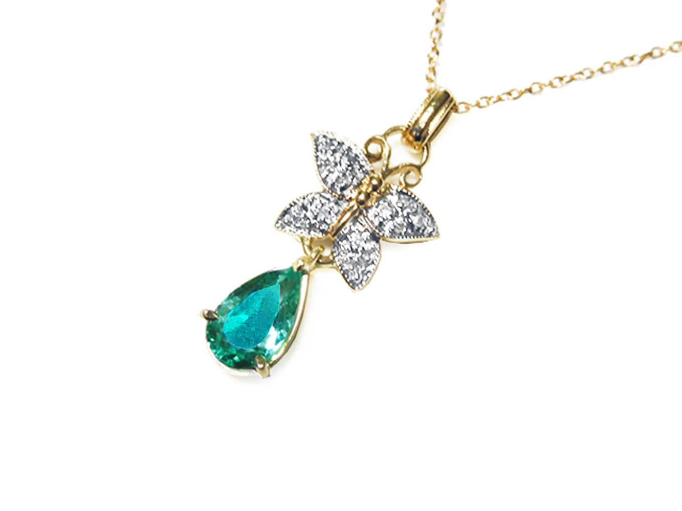 Gold necklace with a colombian teardrop emerald and butterfly pendant on a left-side position, topside visible.