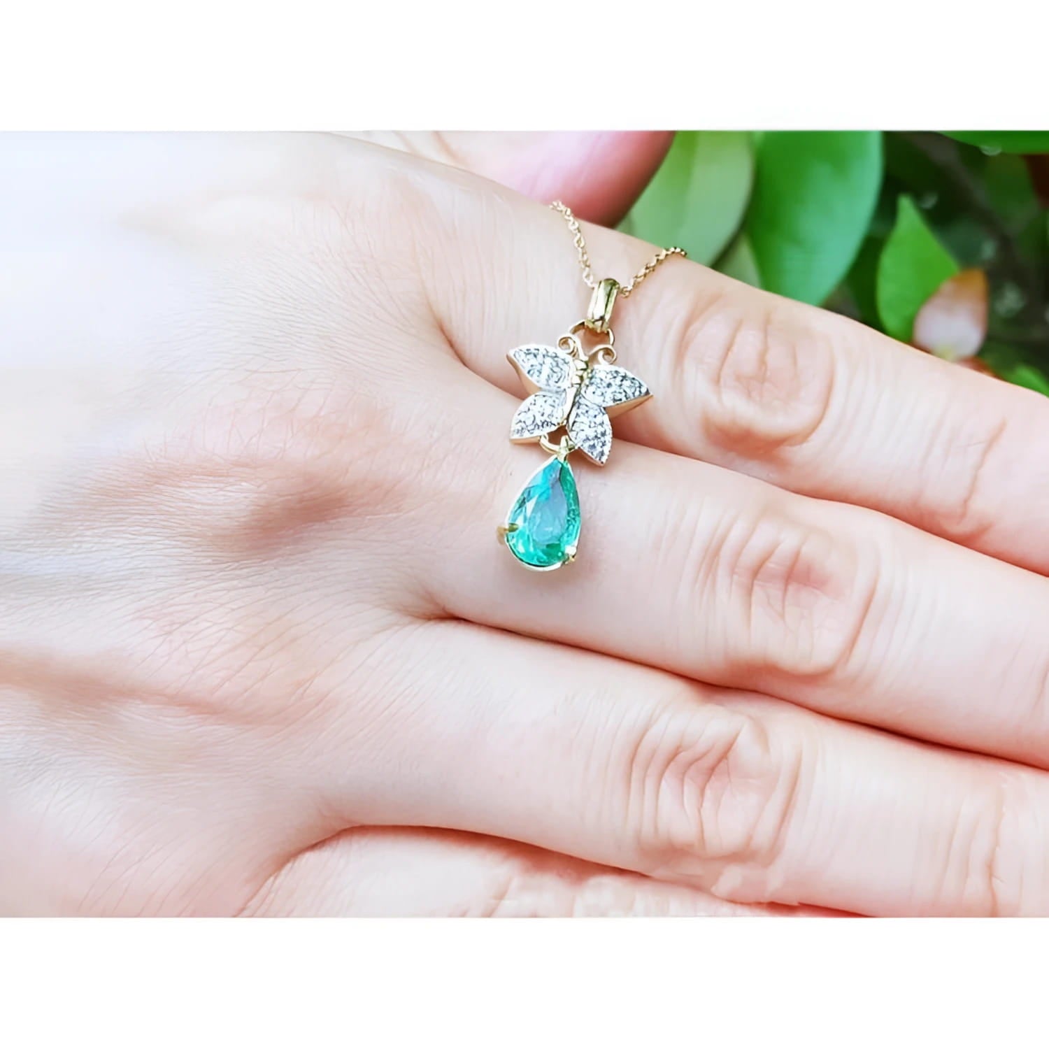 14K gold butterfly pendant with pavé diamonds and a pear-shaped Colombian emerald.