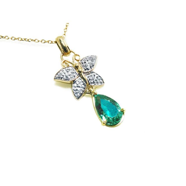 Gold butterfly pendant with natural teardrop emerald and diamond accents on a right position topside view.