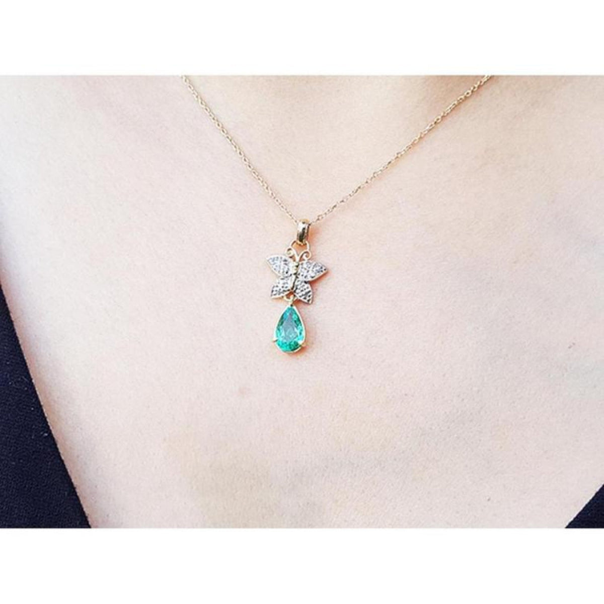14K gold butterfly pendant with pavé diamonds and a pear-shaped Colombian emerald.