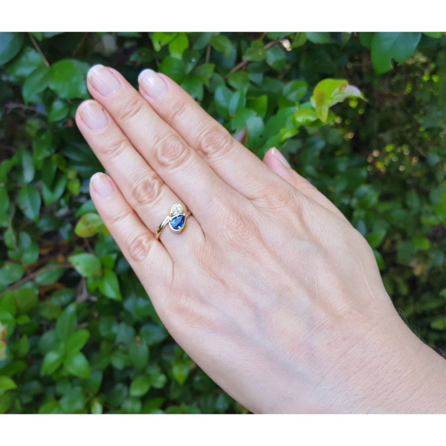 Two-stone "You and Me" blue natural sapphire bypass ring featuring a sparkling teardrop diamond on the side. 
