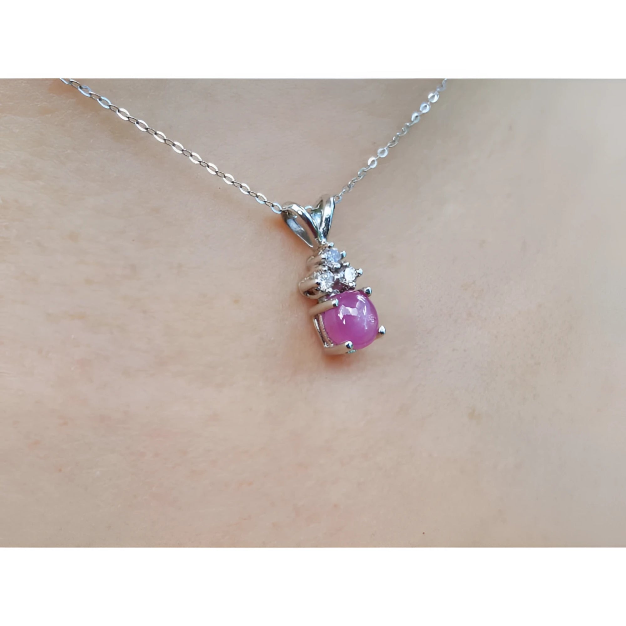 Pink natural sapphire cabochon and diamond necklace on a person's neck.