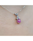 Pink natural sapphire cabochon and diamond necklace on a person's neck.