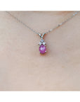 Pink cabochon sapphire pendant on a white gold chain against a skin background.