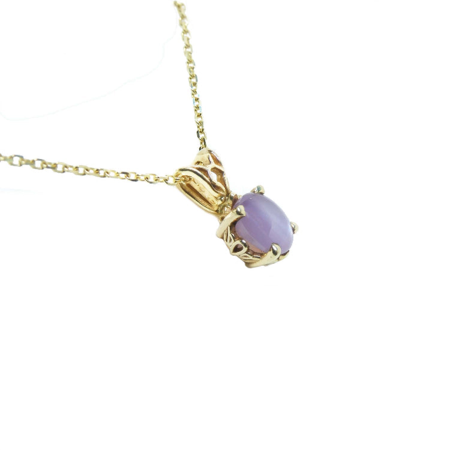 A 14k yellow gold necklace with a pink sapphire pendant with scroll design.