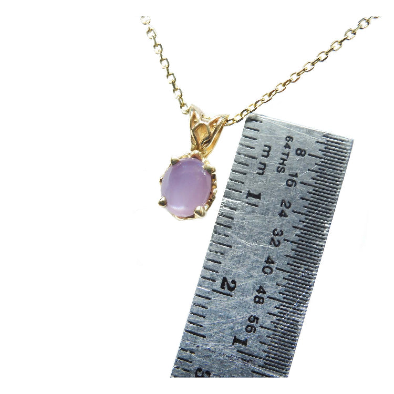 Gold necklace with a pink sapphire solitaire pendant next to a ruler for scale.