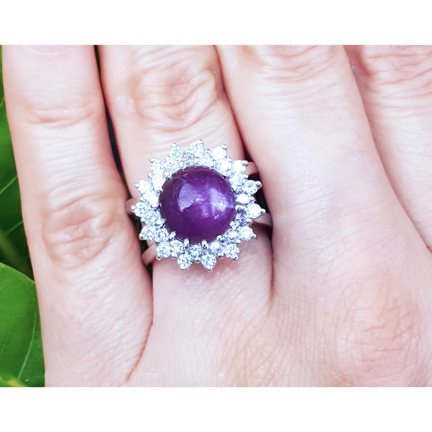 Red purple cabochon star ruby women's ring front top view in a double halo natural diamonds on a hand