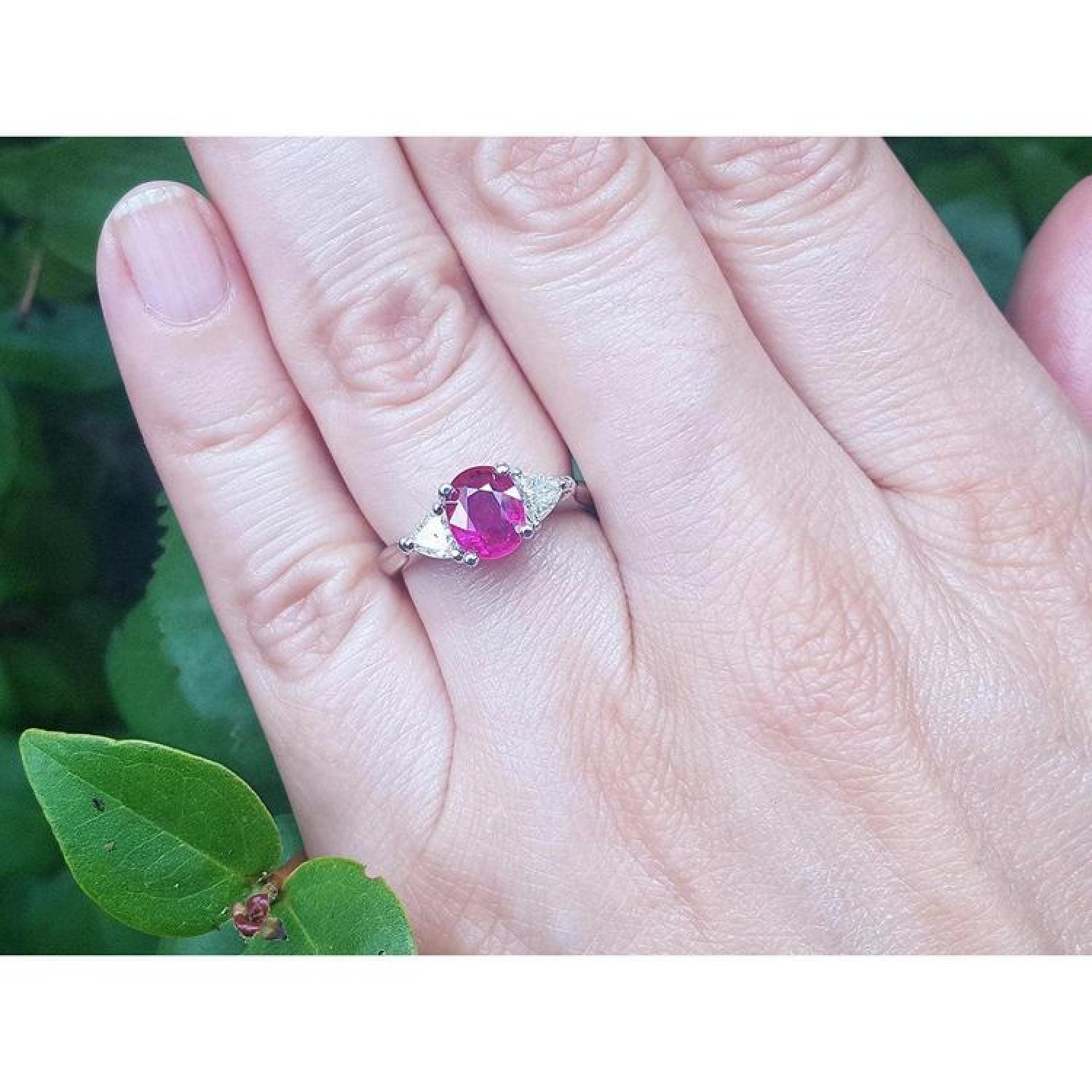 Women's 14k white gold ring with a deep red oval ruby and trillion side diamonds.