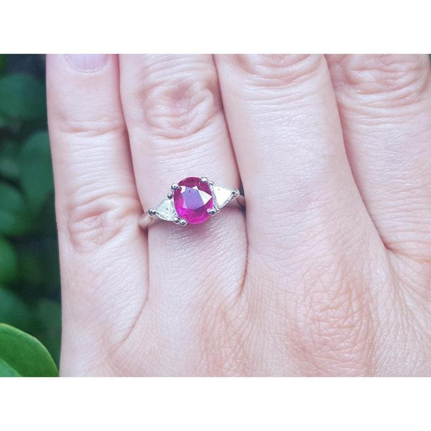 Women's 14k white gold ring with a deep red oval ruby and two trillion side diamonds.