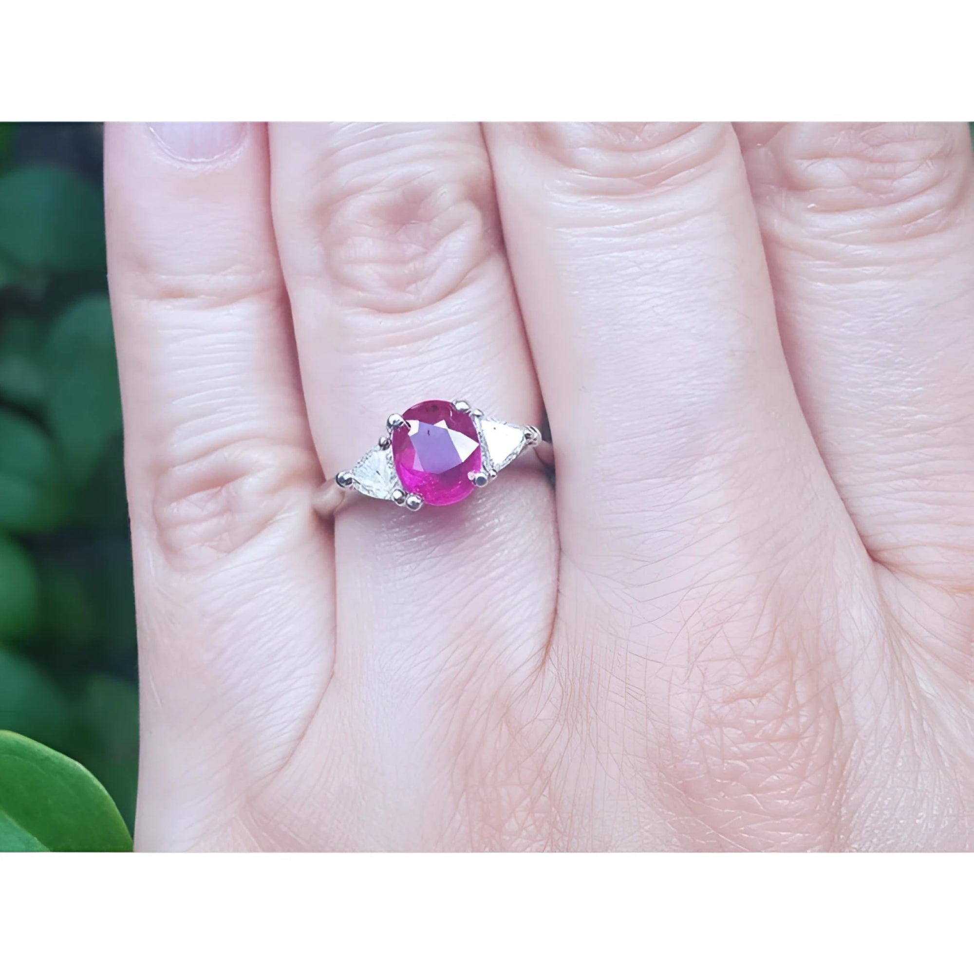 Women's 14k white gold ring with a deep red oval ruby and two trillion side diamonds.